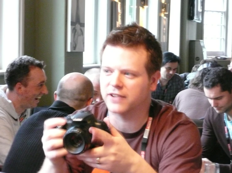 a young man is holding a camera in front of others