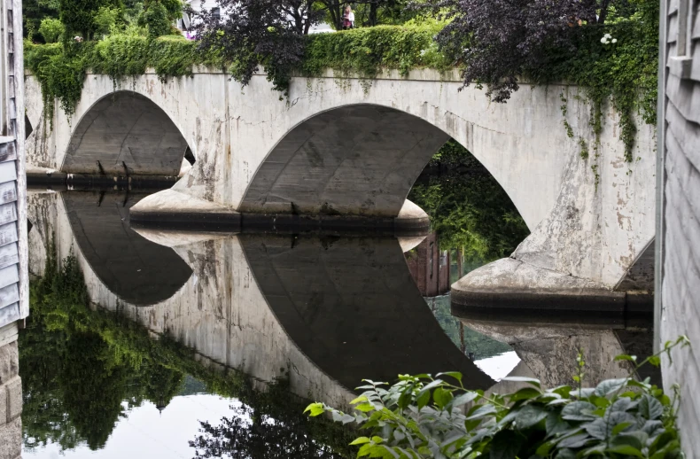 reflection on the water in front of an old stone bridge
