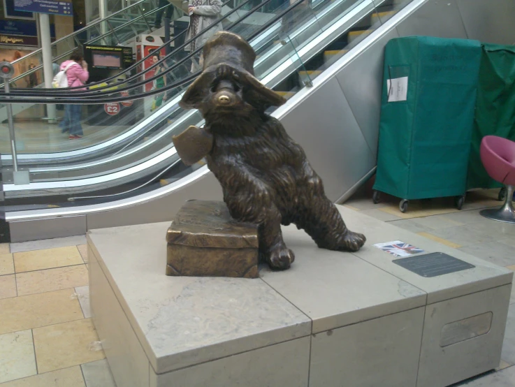 statue of bear at bottom of escalator in shopping mall