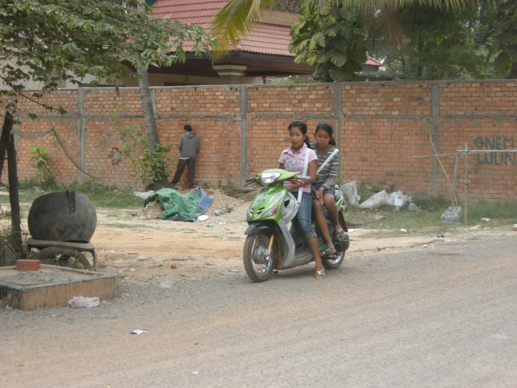 two young children are riding on a scooter