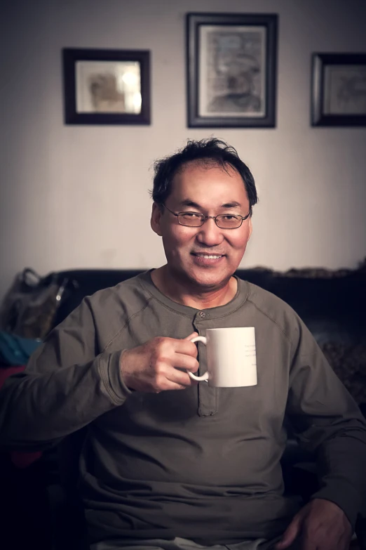 a man holding a cup in his hand smiling