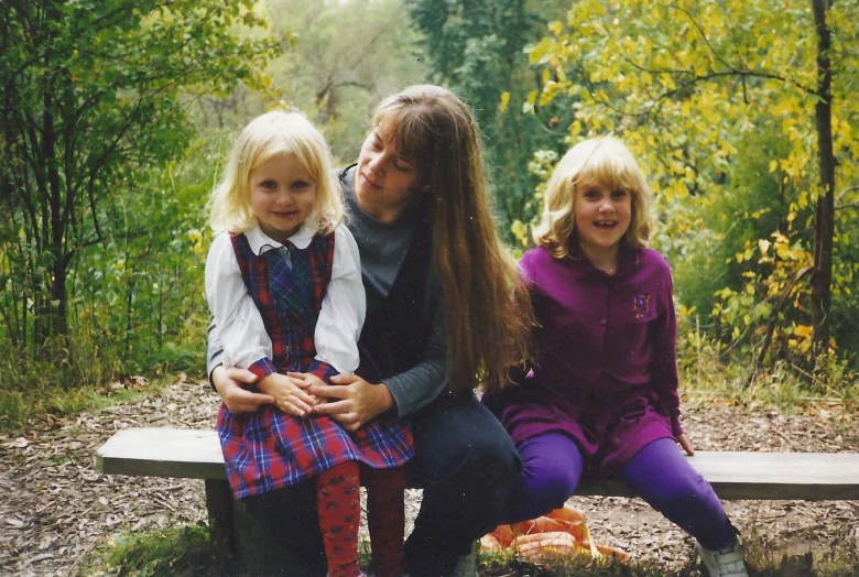 a man and two girls are sitting on a bench