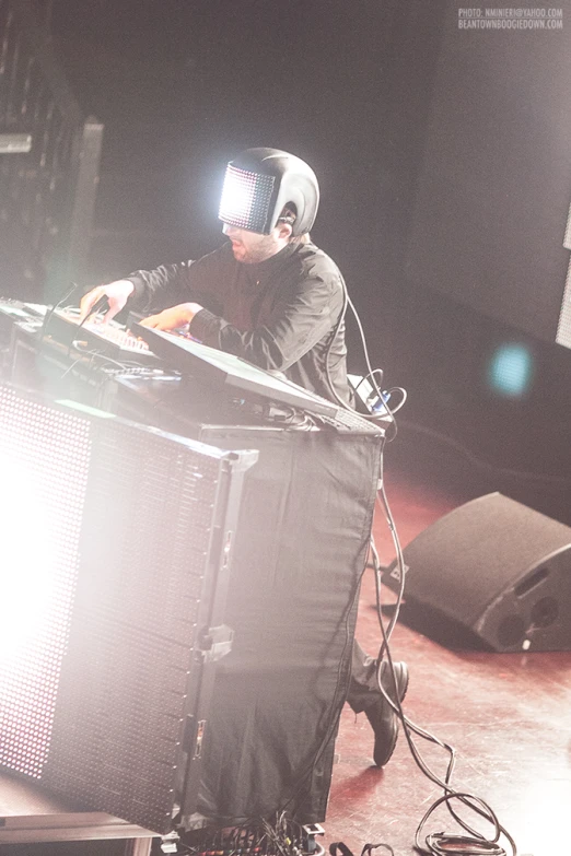 a man playing on stage wearing a large headpiece