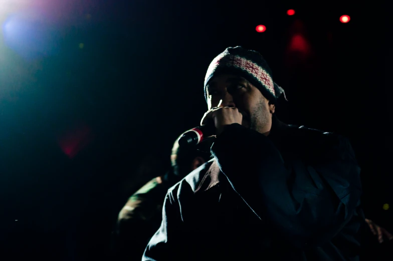 a man wearing a hat singing at a concert