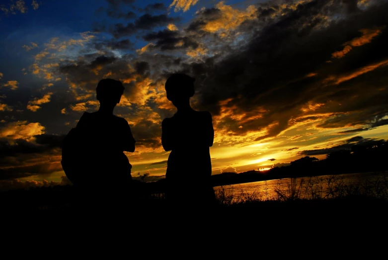 two men stand next to each other as the sun sets