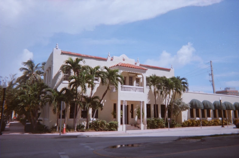 a tall white building with many palm trees around it