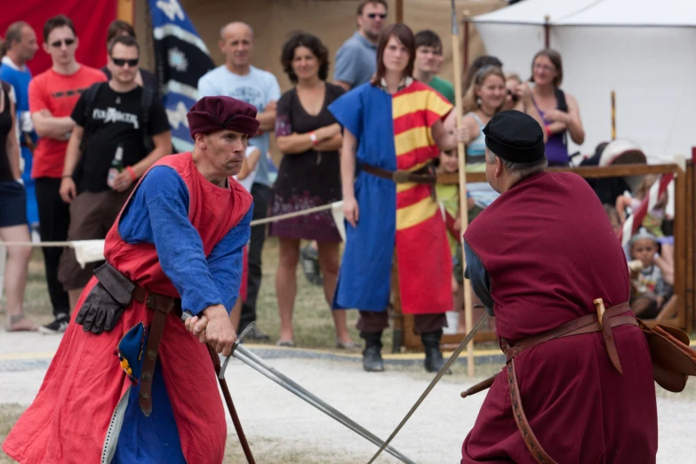men in roman garb on swords with other people behind them