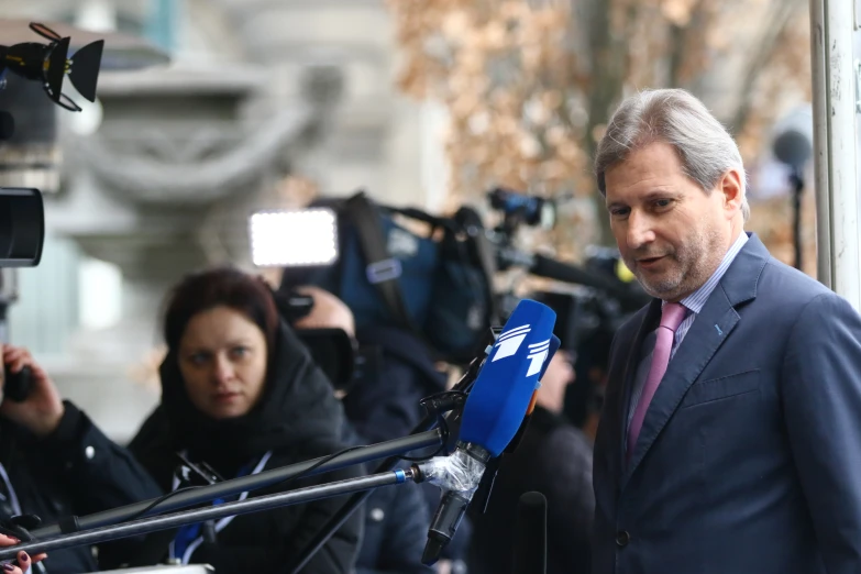 a man in a suit and tie talks into a microphone