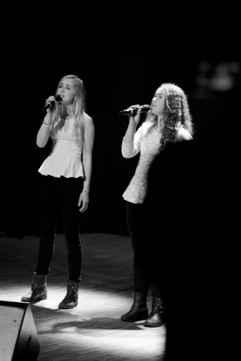 two girls with microphones standing at the end of a stage