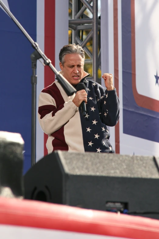a man is in front of a large american flag at an event