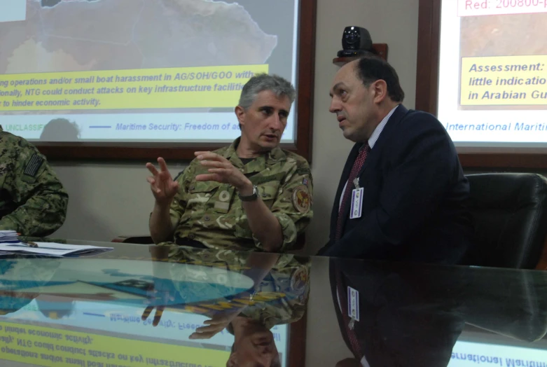 two soldiers are standing around a table in the middle of a meeting