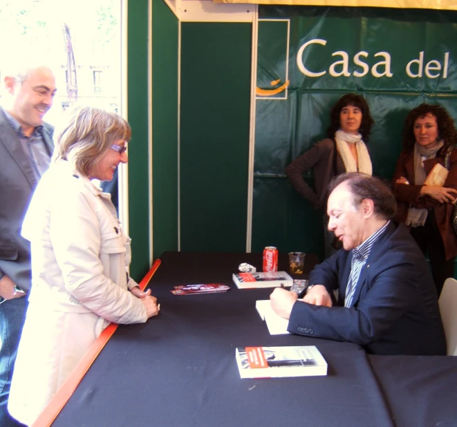 a man in a business suit signing a book at a desk