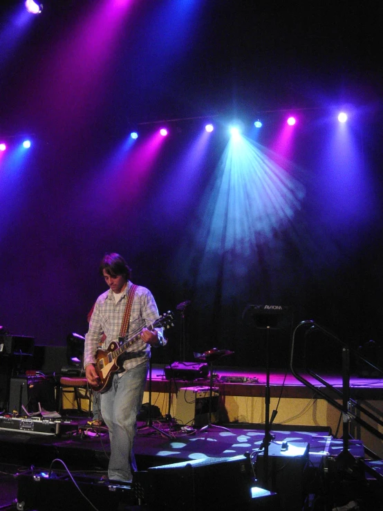 man playing guitar with a lot of lights on the stage