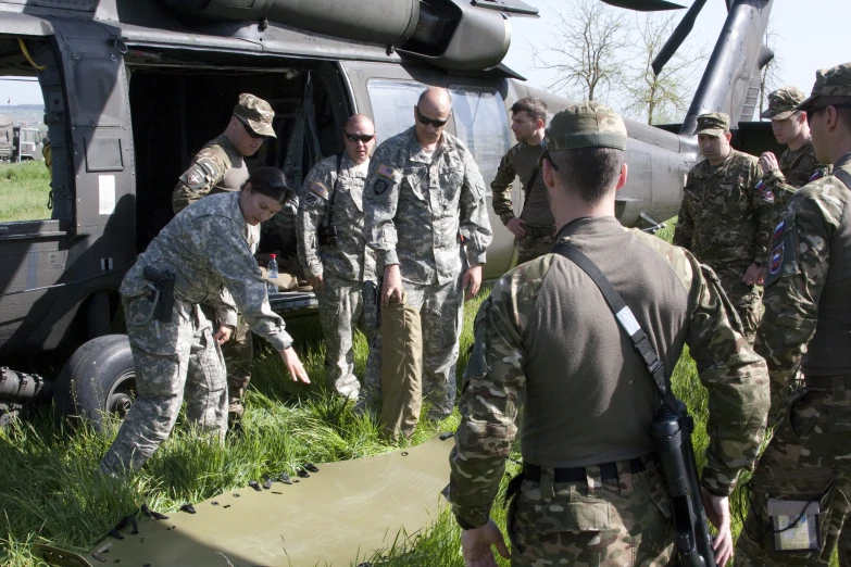 soldiers are talking in front of a helicopter