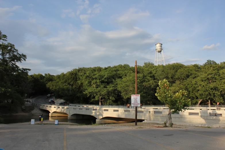 a clock tower towering over a bridge with trees surrounding it