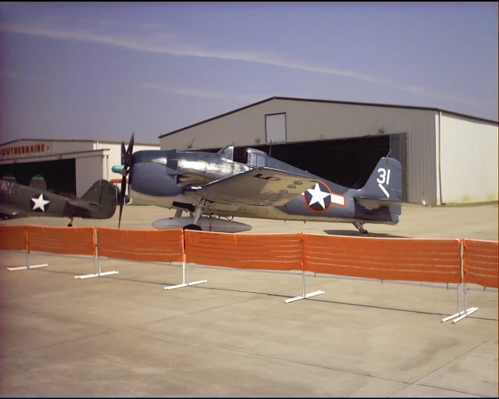 an airplane parked near a hangar with two men standing around it