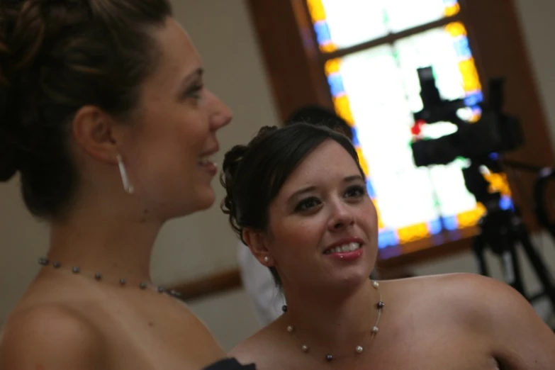 two woman in dresses in front of a stained glass window