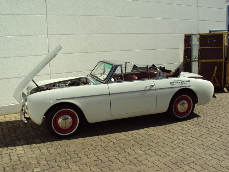 a classic car parked beside a white building