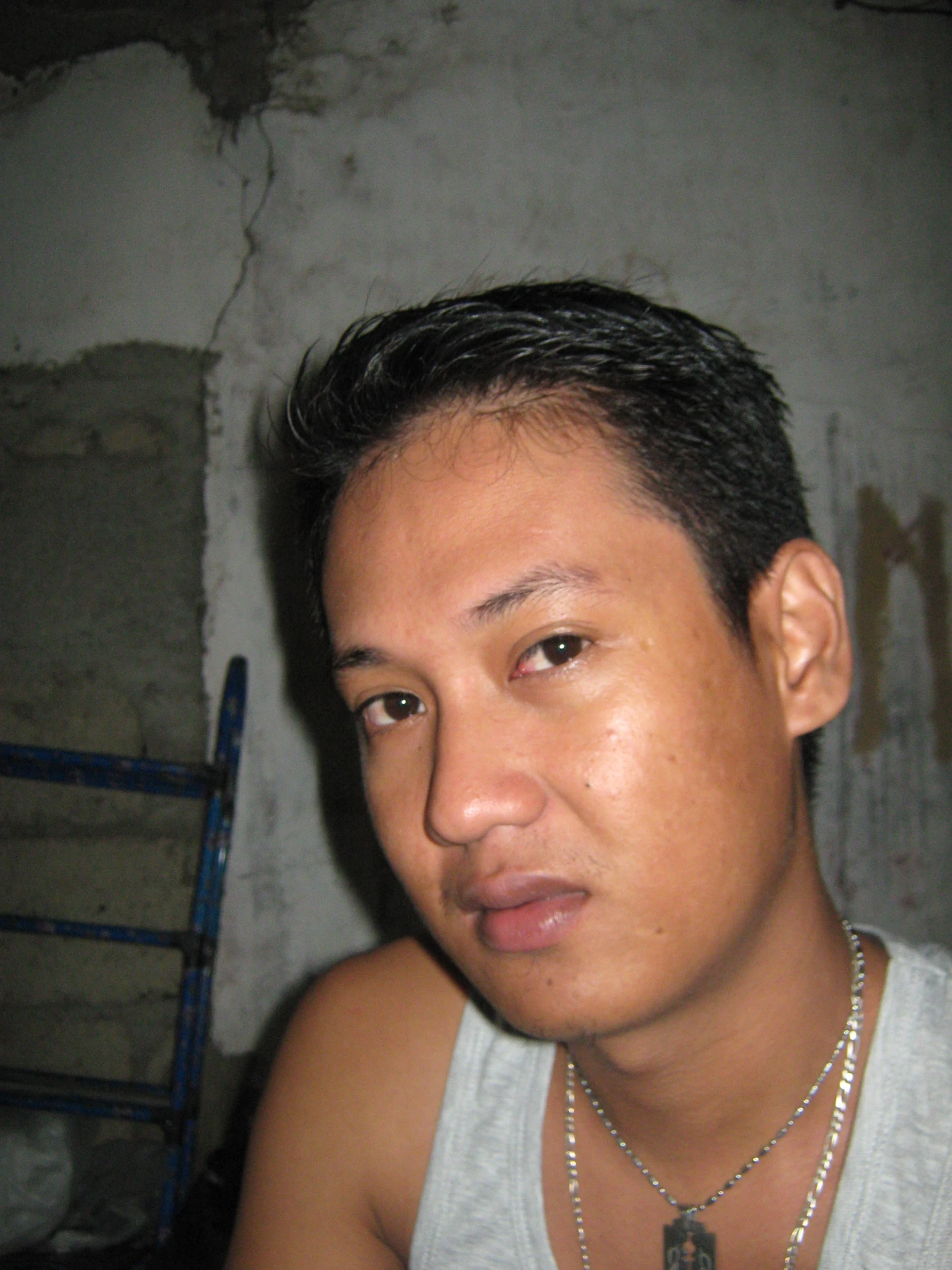 a young man wearing necklaces and looking at the camera