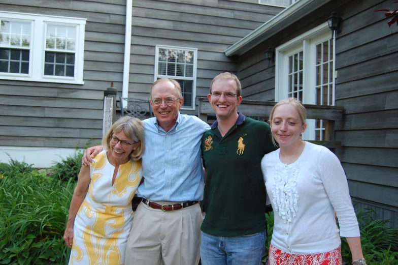 an old man with two women and a child standing in front of a house