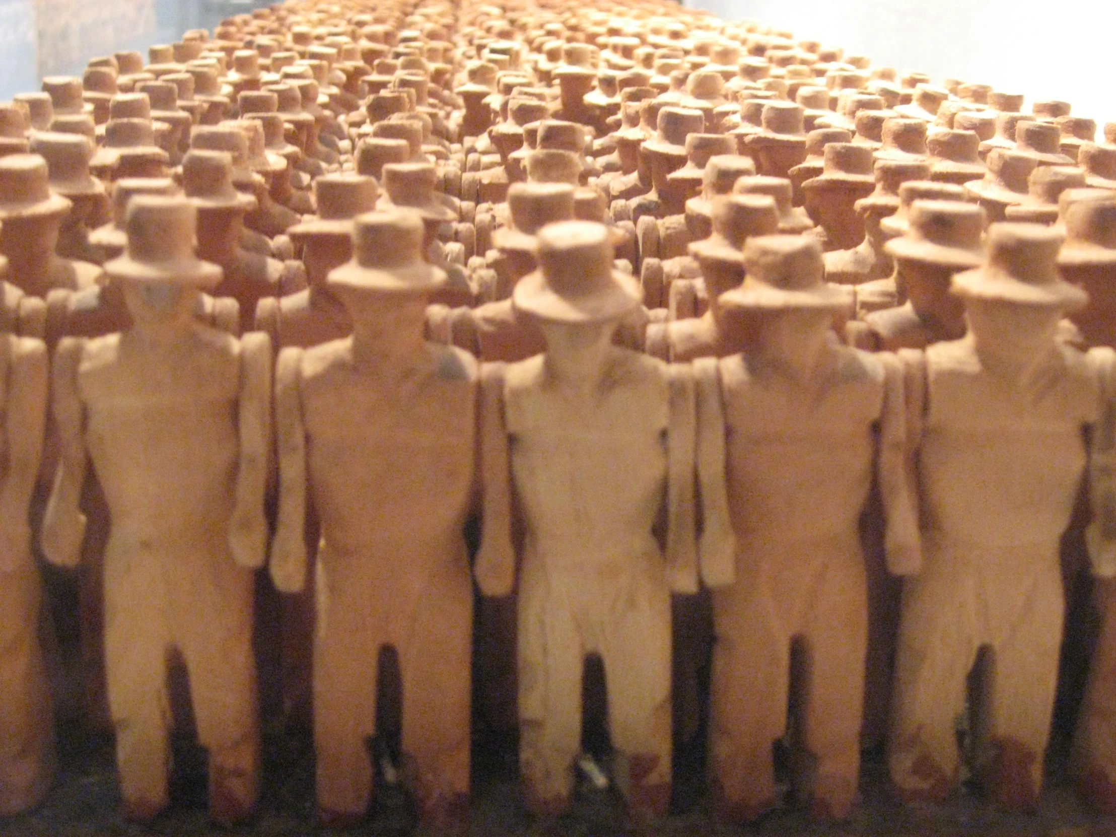 rows of wood men in a museum with brown background