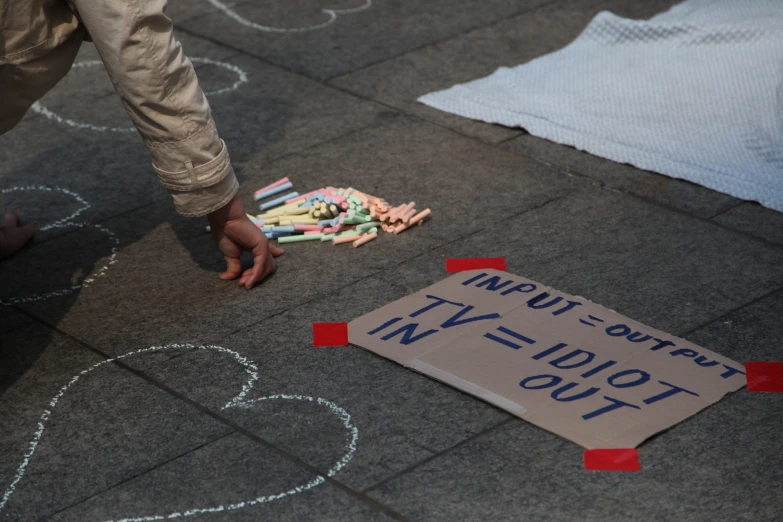 some chalk and paper are on the ground near a sign