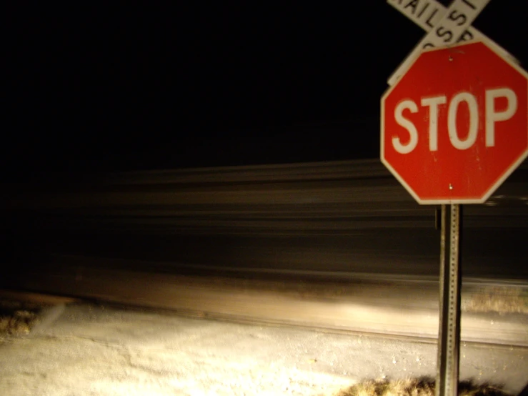 a stop sign is in the foreground and a railroad track in the background