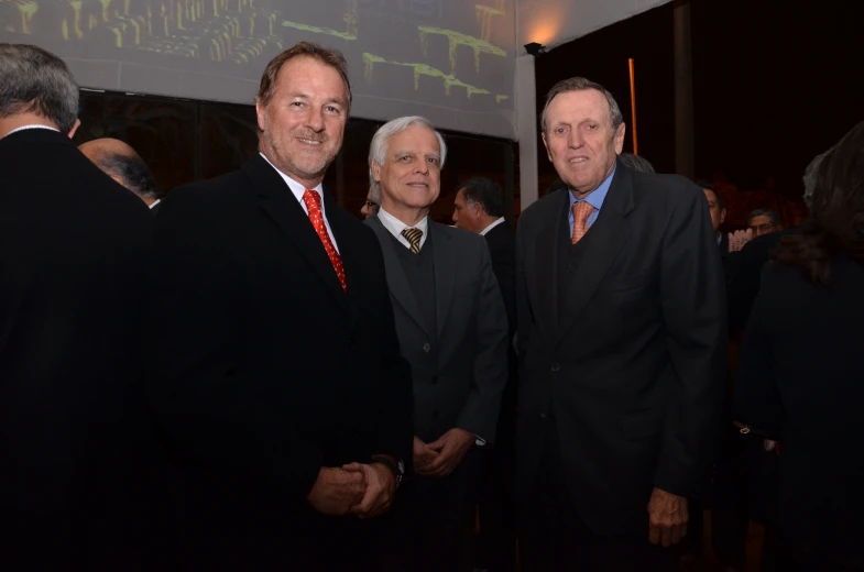 three men in suits stand at the end of a party