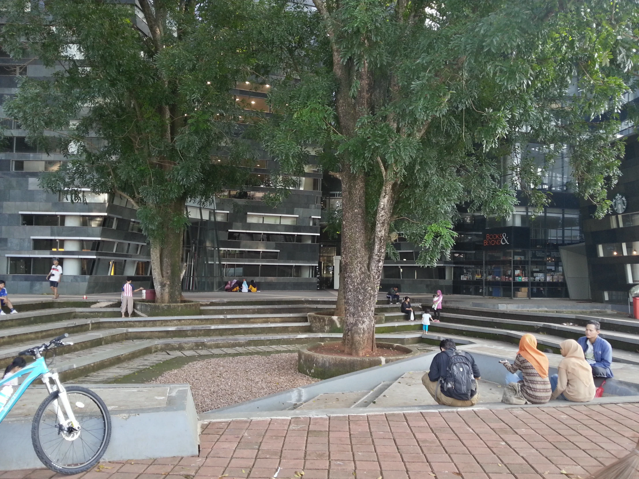 people sit at a bench by the steps in a park