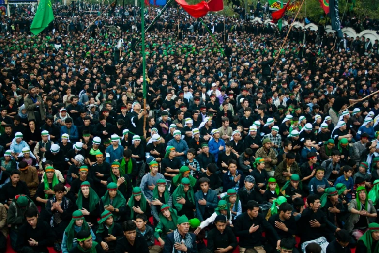 a crowd of people in black coats and green caps and green caps