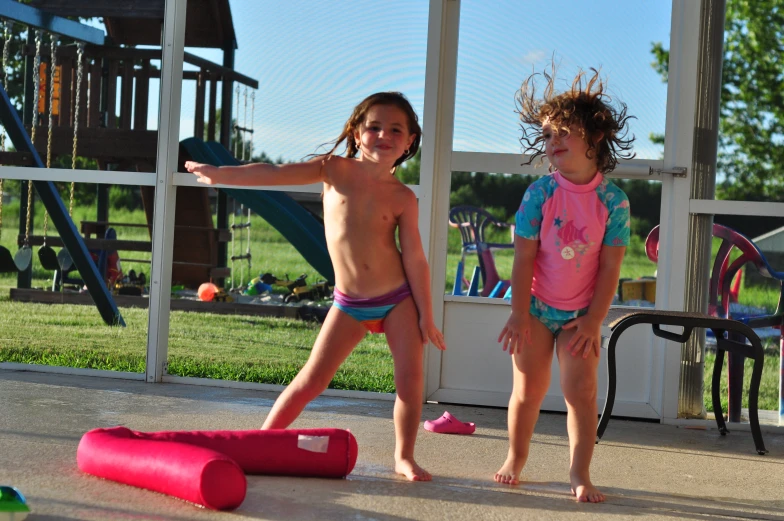 two young s in bathing suits next to a playground