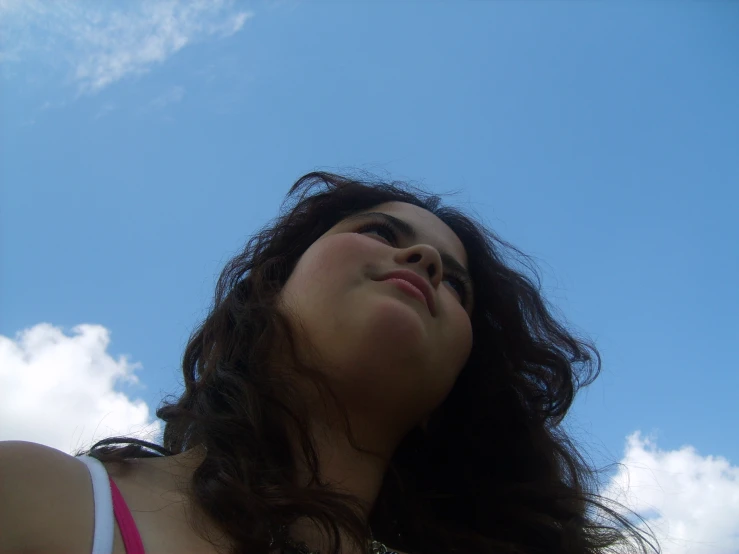a woman looking up at the sky and her hair blowing in the wind