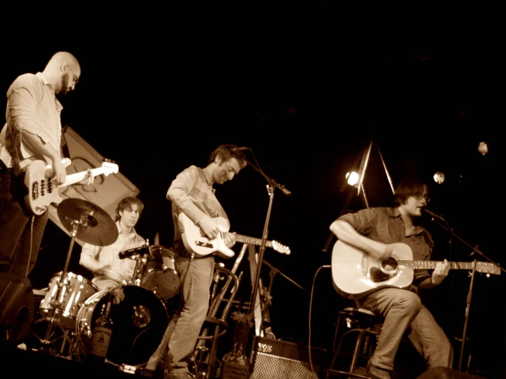 several men in the dark playing guitar at a concert