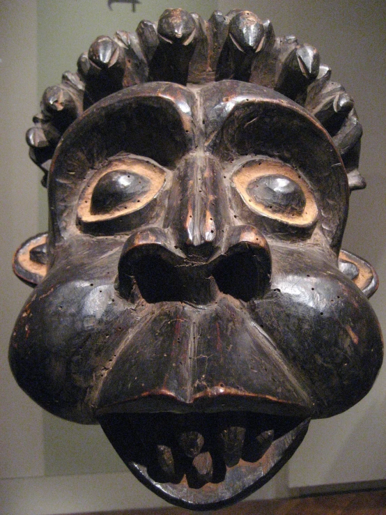 an elaborately designed wooden mask sitting on a table