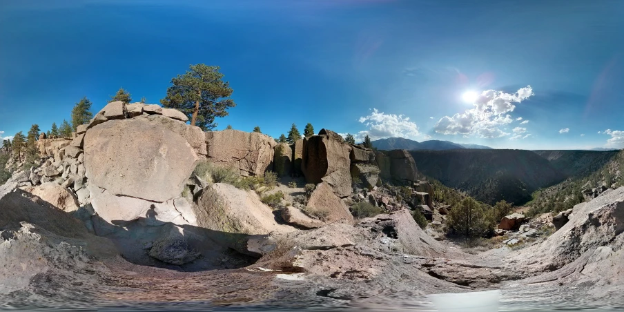 a sunny, rocky mountain with sun in the background