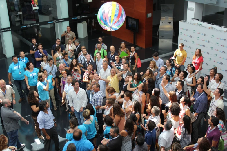 a crowd of people standing around each other and one man holding a glass ballon