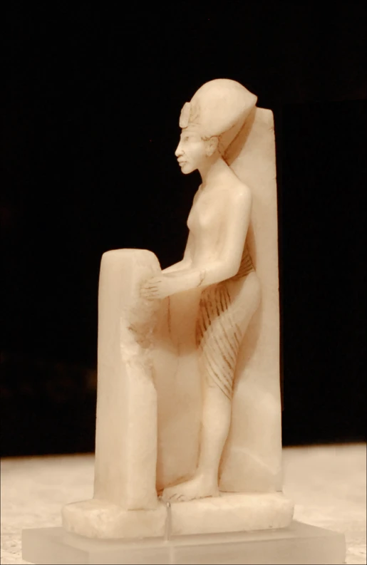 a white statue of a woman sitting on a stone slab