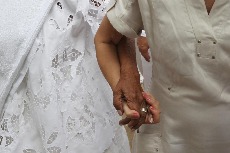 the woman is holding the man's hand while they are dressed in white