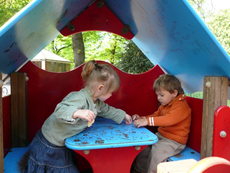 two s are playing together at a play park