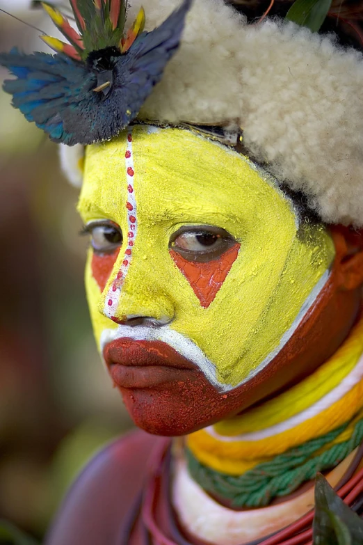 a man with face painted like a yellow woman with a red face and white head band