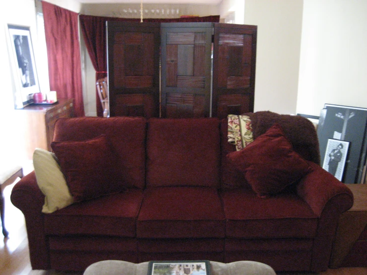 a dark red couch in a living room with dark colored curtains