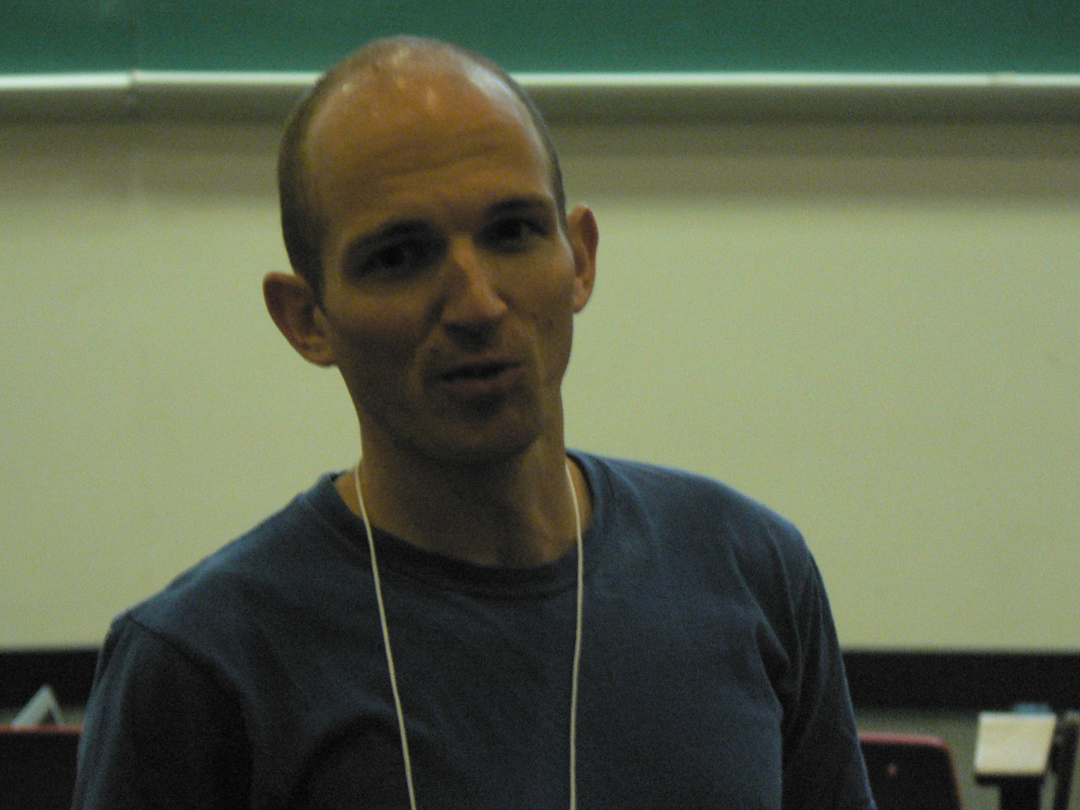 a man wearing a blue shirt and white necklace