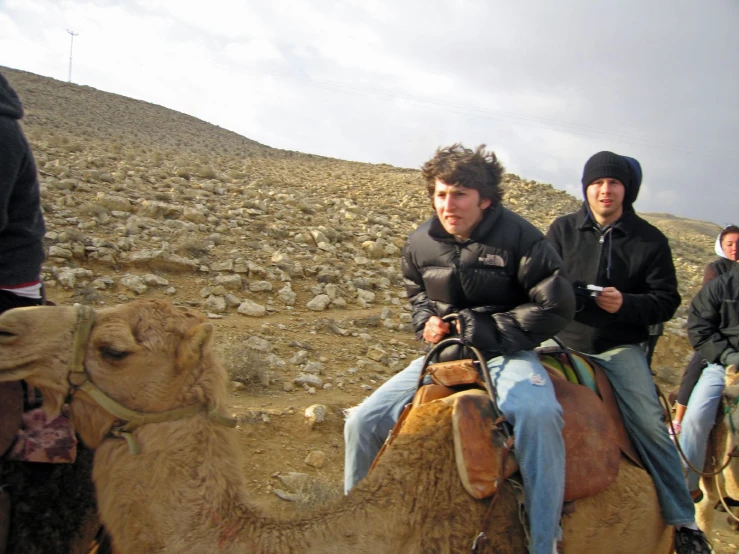 a group of people riding camels down a desert