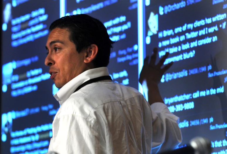 a man wearing a shirt and tie stands in front of a screen