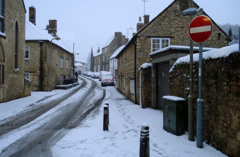 snow covers two rows of stone buildings and three different street signs