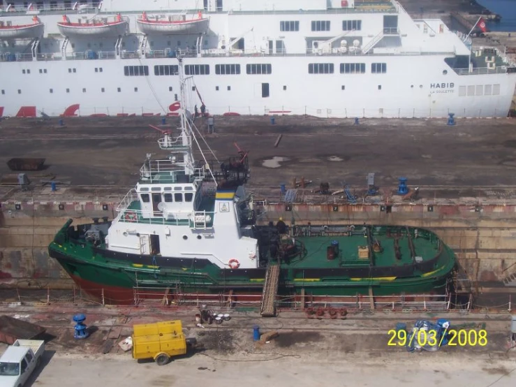 several boats in a dry dock near large white ships