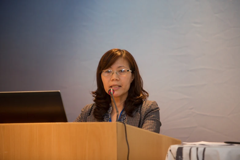 a woman sits behind a podium and gives an empty presentation