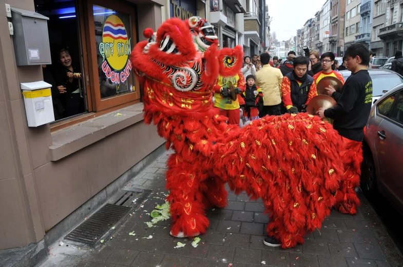 people in costume gather to hear a large red horse