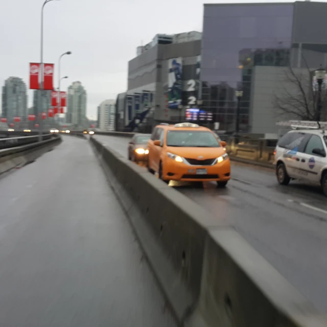 cars driving on a road near tall buildings