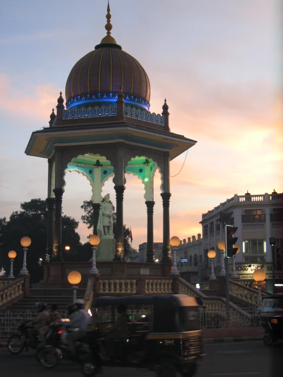 people and vehicles moving in front of a domed structure